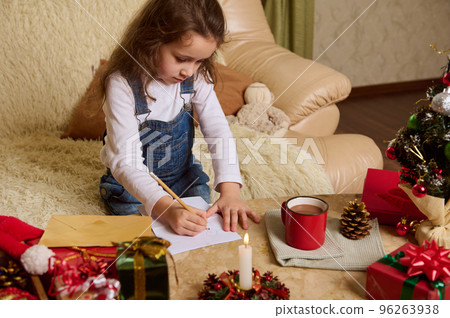 Adorable Caucasian preschool child, a cute little girl draws picture, writes letter to Santa, expecting the upcoming winter holidays. Magical Christmas mood. New Years preparations. December 25 96263938