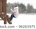 a child on a playground in winter climbs a rope 96263975
