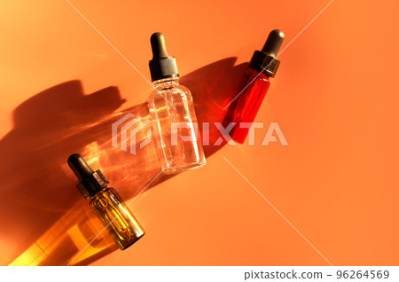 Different glass dropper bottles with serum, oil, gel and beauty products on beige background. Pipette with fluid hyaluronic acid, retinol, vitamin c and a. Natural cosmetics, healthcare, bodycare 96264569