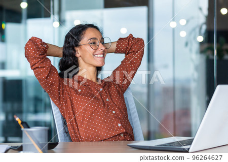 Satisfied happy and successful business woman smiling and resting, hispanic female worker finished work and put her hands behind her head, dreams of victory. Satisfied happy and successful business woman smiling and resting, hispanic female worker finished work and put her hands behind her head, dreams of victory. 96264627