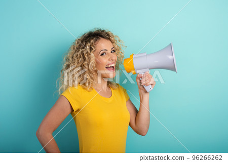 Woman speaks with loudspeaker. joyful expression. cyan background Woman speaks with loudspeaker. joyful expression. cyan background 96266262