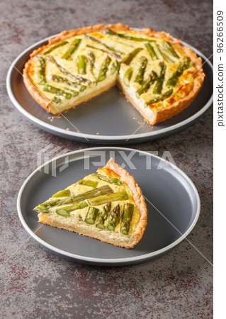 Asparagus Cheese Pie an easy and cheesy tart made with eggs, asparagus, and onions close-up in a plate. Vertical 96266509