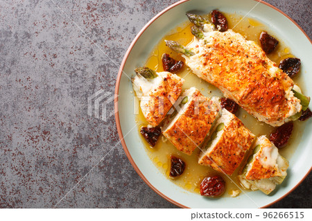 Chicken meat stuffed with fresh asparagus, mozzarella cheese and sun-dried tomatoes served with fragrant sauce close-up in a plate. Horizontal top view Chicken meat stuffed with fresh asparagus, mozzarella cheese and sun-dried tomatoes served with fragrant sauce close-up in a plate. Horizontal top view 96266515