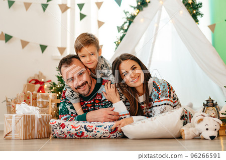 Happy parents play with their little son in a teepee during Christmas holidays Happy parents play with their little son in a teepee during Christmas holidays 96266591
