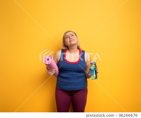 Fat girl does gym at home. tired expression. Yellow background 96266676
