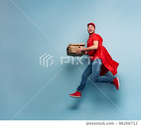 Deliveryman with pizzas acts like a powerful superhero. Concept of success and guarantee on shipment. Studio cyan background 96266712