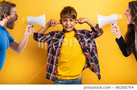 Child covers his ears because he does not want to hear the cries and reproaches of his parents. Yellow background Child covers his ears because he does not want to hear the cries and reproaches of his parents. Yellow background 96266764