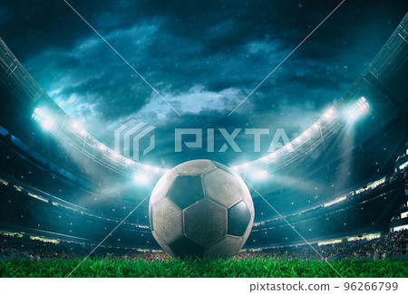 Close up of a soccer ball in the center of the stadium illuminated by the headlights 96266799