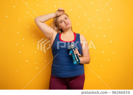 Fat girl does gym at home. tired expression. Yellow background 96266839