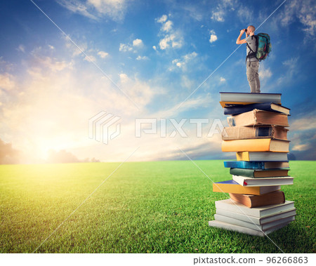 Man with binoculars over a pile of books observe a colorful sunrise. the culture open the imagination 96266863