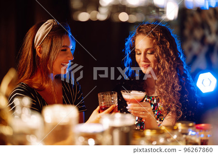 Coctails party. ?ocktail in the hands of a woman. Young woman drinking cocktails in bar. Coctails party. ?ocktail in the hands of a woman. Young woman drinking cocktails in bar. 96267860