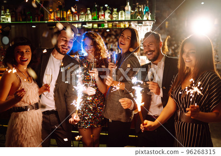 Glowing sparkles in hands. Group of happy people enjoying party with fireworks. Winter holiday. 96268315