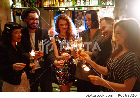 Glowing sparkles in hands. Group of happy people enjoying party with fireworks. Winter holiday. 96268320