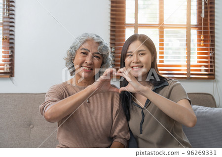 Loving adult daughter hugging older mother on couch at home, family enjoying tender moment together, young woman and mature mum or grandmother looking at each other, two generations 96269331