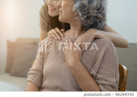 Loving adult daughter hugging older mother on couch at home, family enjoying tender moment together, young woman and mature mum or grandmother looking at each other, two generations Loving adult daughter hugging older mother on couch at home, family enjoying tender moment together, young woman and mature mum or grandmother looking at each other, two generations 96269350