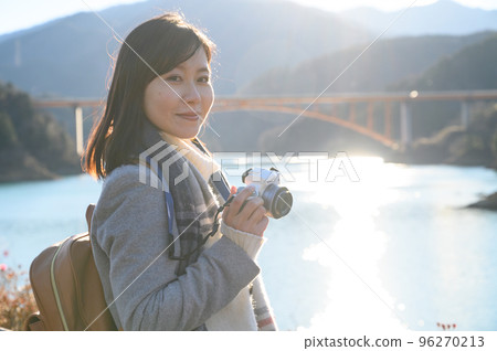 夕陽下湖邊拍照的女人 96270213