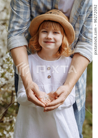 The hands of an adult and a child hold a flower 96272092