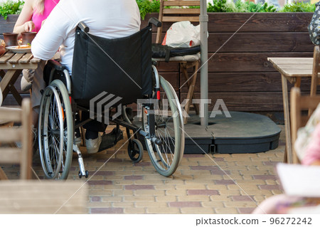 Unrecognizable woman with disability sitting in wheelchair in the street close up Unrecognizable woman with disability sitting in wheelchair in the street close up 96272242