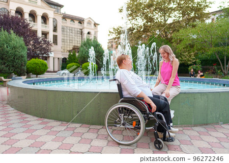 Young daughter taking care of her mother with disability sitting in wheelchair 96272246