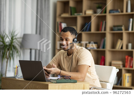 Online Education. Arab male teacher having video chat with students, using laptop and wearing wireless headphones Online Education. Arab male teacher having video chat with students, using laptop and wearing wireless headphones 96272563