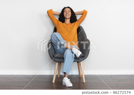 Joyful brunette woman resting in arm chair with closed eyes 96272574