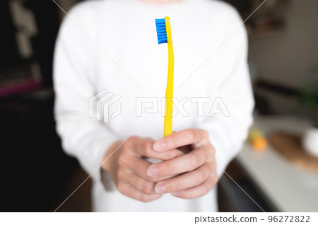 bright toothbrush in female hands in the foreground, the background of the room is blurred 96272822