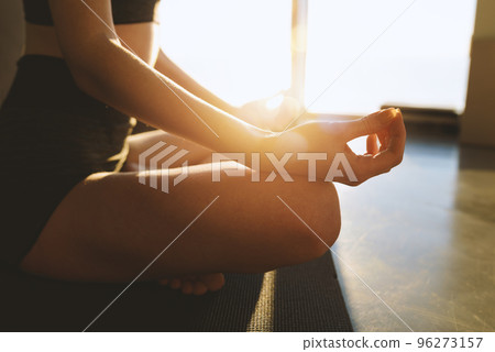 Young girl relaxing in yoga position in front of a bright window Young girl relaxing in yoga position in front of a bright window 96273157