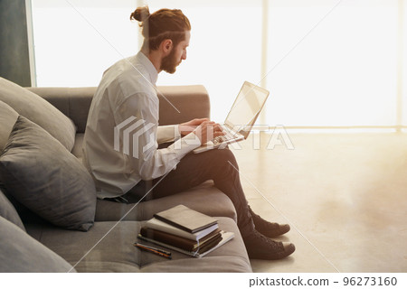 Businesman works on sofa with his laptop. he is in smart working 96273160