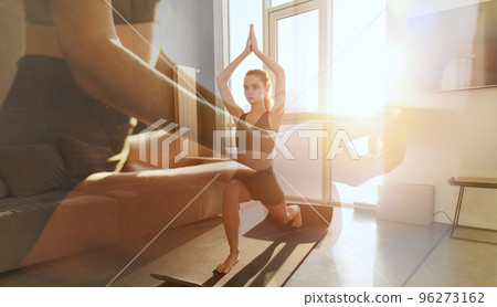 Young girl relaxing in yoga position in front of a bright window Young girl relaxing in yoga position in front of a bright window 96273162