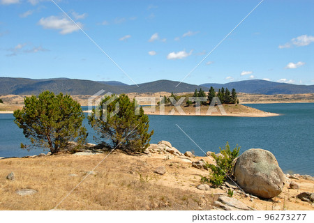 Jindabyne, New South Wales, Australia: View over Lake Jindabyne with trees and rocks in the foreground. Jindabyne is a tourist destination near the Snowy Mountains. 96273277