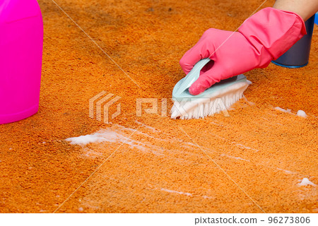 Woman Hand Cleaning Stain On Carpet With hard brush. Orange carpet cleaning. carpet cleaning service concept 96273806