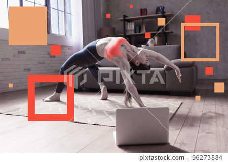 Young woman follows with a laptop a gym exercises. She is at home due to coronavirus codiv-19 quarantine 96273884