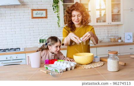 Mother and daughter prepare a cake together in the kitchen 96274513