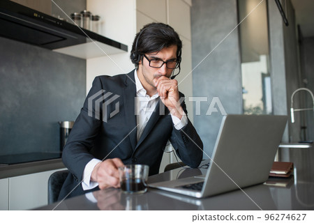 Businessman works from remote at house with a laptop due to coronavirus quarantine. Businessman works from remote at house with a laptop due to coronavirus quarantine. 96274627