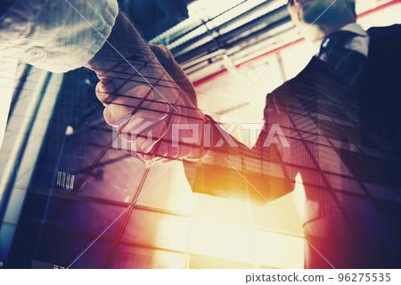 Handshaking business person in office. concept of teamwork and partnership. double exposure Handshaking business person in office. concept of teamwork and partnership. double exposure 96275535
