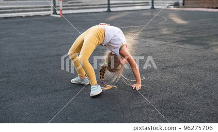 Caucasian girl doing bridge exercise on sports ground outdoors. Caucasian girl doing bridge exercise on sports ground outdoors. 96275706