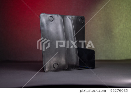 Smartphone lies inside slot of oblong black leather wallet 96276085