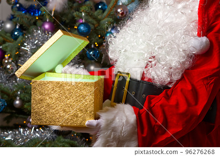 Santa Claus opening magic glowing gift box with Christmas tree on back side 96276268