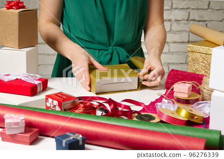 Gift wrapping for Christmas and New Year. Handmade. girl's hands with gift ribbon, twine, tape and present wrapped Gift wrapping for Christmas and New Year. Handmade. girl's hands with gift ribbon, twine, tape and present wrapped 96276339