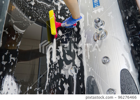 Cleaning of shower steam cabins from calcium deposits. Cleaning in the bathroom. hand in gloves with rag and detergent washing shower and glass Cleaning of shower steam cabins from calcium deposits. Cleaning in the bathroom. hand in gloves with rag and detergent washing shower and glass 96276466