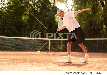 Young man in white tshirt with a tennis racket in hands Young man in white tshirt with a tennis racket in hands 96276630
