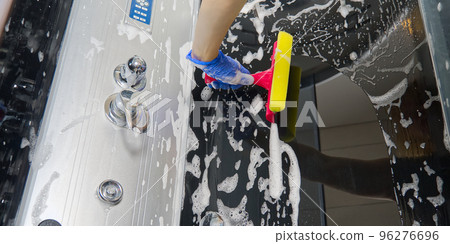 Cleaning of shower steam cabins from calcium deposits. Cleaning in the bathroom. hand in gloves with rag and detergent washing shower and glass Cleaning of shower steam cabins from calcium deposits. Cleaning in the bathroom. hand in gloves with rag and detergent washing shower and glass 96276696