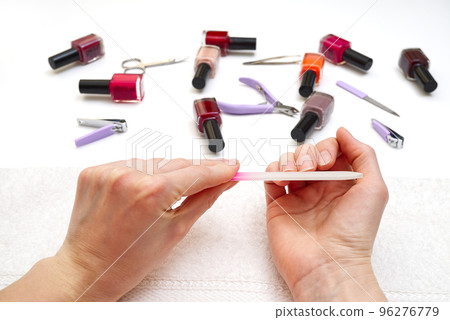 Manicure. Closeup of a woman hand polishing nails manicure. Nail technician manicure at nail salon. Young caucasian woman receiving a french manicure. Manicure. Closeup of a woman hand polishing nails manicure. Nail technician manicure at nail salon. Young caucasian woman receiving a french manicure. 96276779