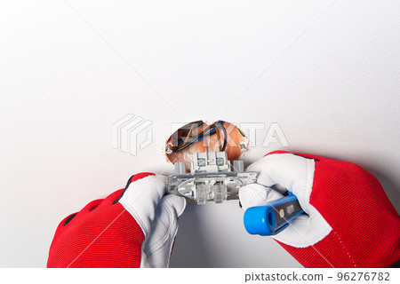 electrician installing light switch on painted wall with screwdriver. Man installing light switch after home renovation. 96276782