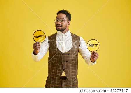 Portrait of excited man showing icons with nft and token Portrait of excited man showing icons with nft and token 96277147