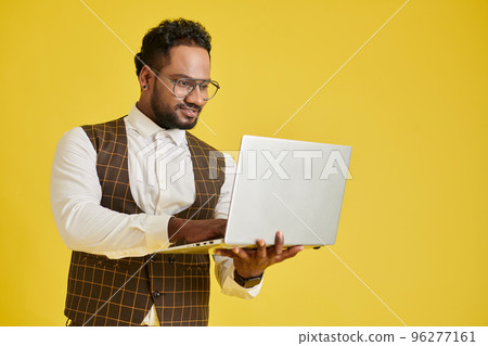 Positive project manager working on laptop, isolated on yellow 96277161