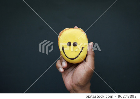 holding a smile face design donuts against black background holding a smile face design donuts against black background 96278892