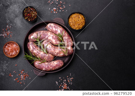 Raw pork sausages grill with spices and herbs on a dark concrete table 96279520