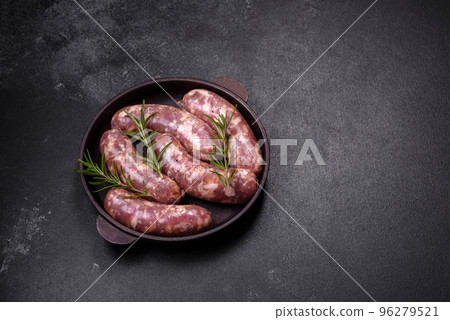 Raw pork sausages grill with spices and herbs on a dark concrete table 96279521