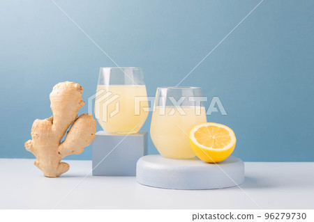 Antioxidant drink fresh ginger lemon in a glass trendy blue background, podium minimalism, balance 96279730